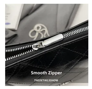 Detailed macro view of smooth silver metal zipper on black quilted chain handbag