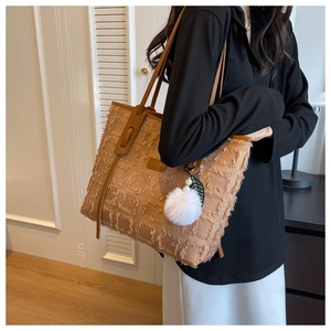 Close-up of khaki textured canvas tote bag with brown faux leather straps and white fur ball