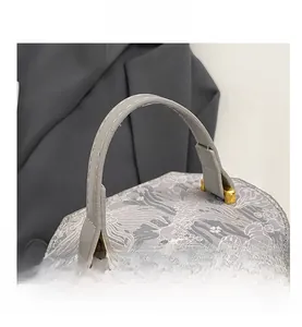 Detail of grey patterned bucket bag featuring premium leather handle and gold metal buckles