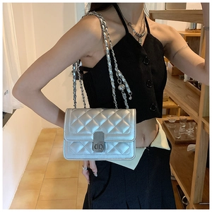 Detailed view of silver quilted chain bag with metallic finish and metal ball charm