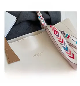 Detail view of cream tote bag with brown leather strap and colorful silk scarf decoration