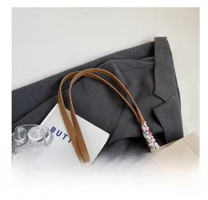 Detail of white leather tote with brown handles and a decorative geometric silk scarf