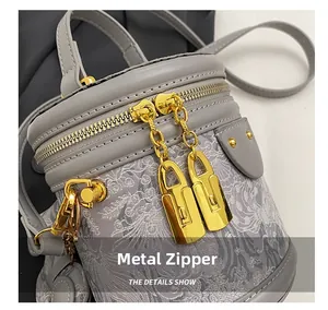 Detail of high-quality gold hardware zippers on a gray embroidered bucket bag