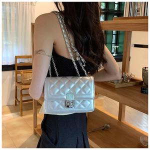 Detail of silver quilted chain bag featuring metallic finish and square clasp closure