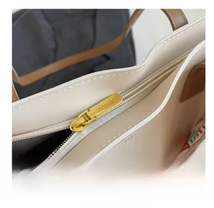 Detail shot of the golden zipper on a beige tote bag with fine stitching and SOUKU logo