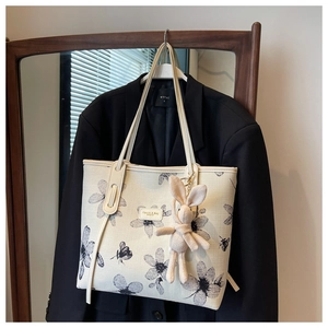 Detail of canvas tote bag with floral print and cute rabbit plush charm decoration