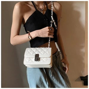 Quilted white crossbody bag with chain strap shown on model in a soft indoor setting