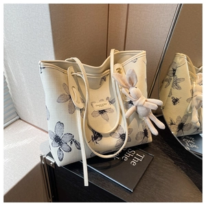 Detail of floral canvas tote bag with black flower print and beige rabbit charm accessory
