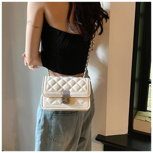Rear view of model wearing white quilted crossbody bag with golden chain strap