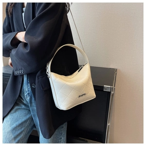 Close-up of beige quilted leather bucket bag with silver chain strap on model