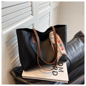 Close-up of black tote bag with brown handles and a colorful silk scarf decoration