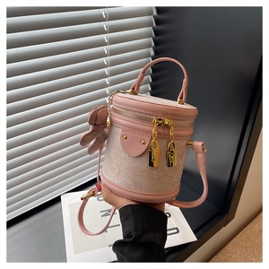 Detail of pink cylindrical bucket bag with jacquard floral pattern and golden hardware