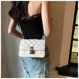 Detailed view of the white quilted chain bag with silver twist lock on a model