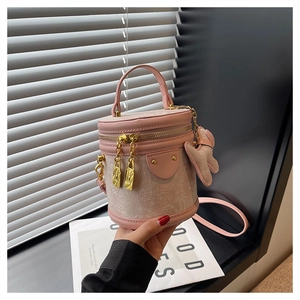 Detailed shot of pink textured mini bucket bag with gold zipper and bunny charm