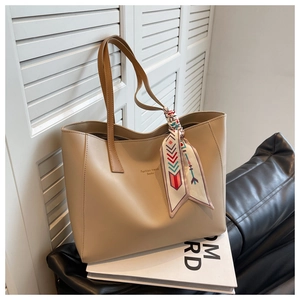 Detail of beige tote bag with gold lettering and decorative ethnic floral scarf handle