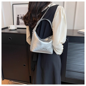 Silver quilted chain bag shown on model's shoulder with metallic branding detail