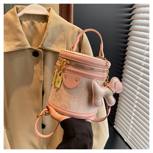 Close-up of pink bucket bag with gold hardware and a cute puppy plush charm