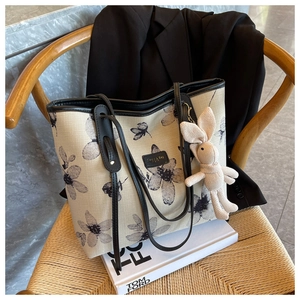 Détail du grand cabas en toile avec imprimé fleuri, garniture cuir et charm lapin sur chaise