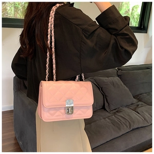 Model wearing a pink quilted crossbody bag with chain strap and gold turn-lock closure