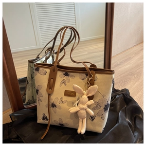 Detail of canvas tote bag with floral print, leather strap and pink rabbit charm