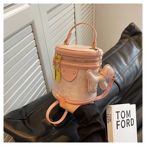 Detail of pink cylindrical bucket bag featuring floral lace embroidery and a dog charm