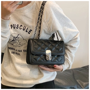 Detail of black quilted leather shoulder bag featuring silver metal chain and rotary lock