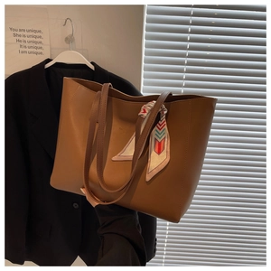 Detail of dark brown leather tote bag with decorative silk scarf and textured finish