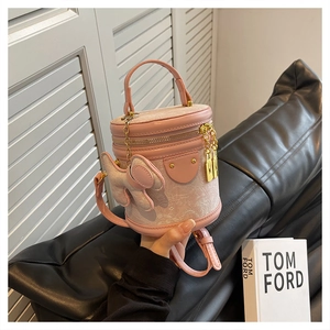 Pink bucket bag with cute elephant charm and woven floral fabric details in hand