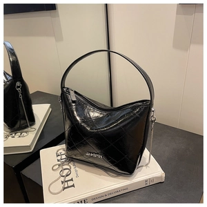 Detail of black quilted chain bag featuring glossy leather texture and silver metal hardware
