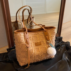 Caramel canvas tote bag with fringed grid texture and plush ball charm on black silk