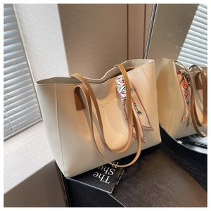 Detail view of large cream tote bag with brown straps and decorative printed silk scarf