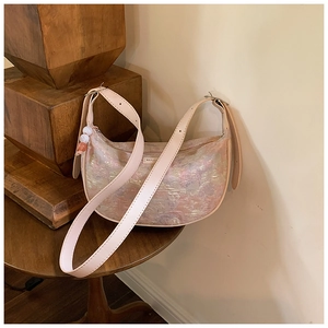 Detail of the pearlescent jacquard fabric and beaded charm on this crescent shoulder bag