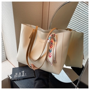 Detail of minimalist cream tote bag with brown straps and colorful silk scarf accessory