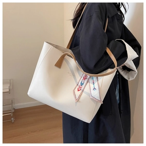 Detail of white tote bag with brown straps and colorful silk scarf accessory on side