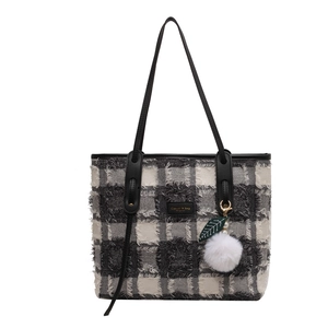 Classic black and white tweed tote bag with fringe edges and plush charm accessory