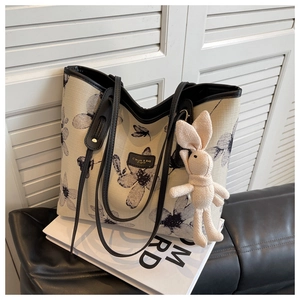 Detail of floral woven tote bag with black leather handles and cute rabbit charm
