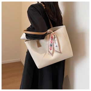 Detail of cream tote bag with silk scarf on shoulder strap and thin brown handles
