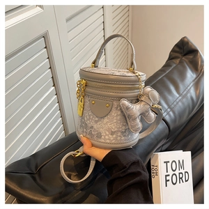 Detail of grey bucket bag with white cloud texture, gold lock, and dog charm ornament
