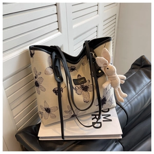 Detail of off-white canvas tote with grey floral patterns and a cute rabbit pendant