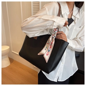Detailed view of black faux leather tote bag with printed silk scarf on the handle