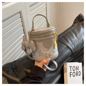 Detail of grey mini bucket bag with textured fabric, leather handle and bow accessory