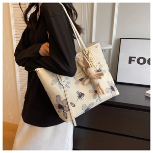 Detailed view of beige canvas tote bag with floral patterns and a cute rabbit charm