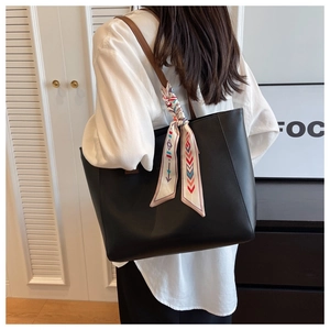 Large black tote bag with brown straps and a geometric patterned scarf for commute
