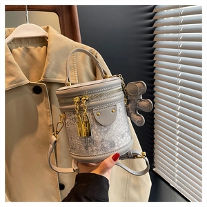 Detail of light gray cylindrical bucket bag with jacquard patterns and cute bear charm