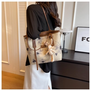 Detailed side view of large canvas tote bag with floral patterns and a cute rabbit charm