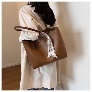 Detail of large brown leather tote bag with decorative silk scarf and fashion text