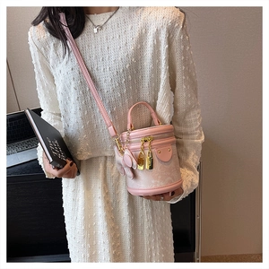 Detail of pink cylinder bucket bag featuring lace texture and golden lock pendants