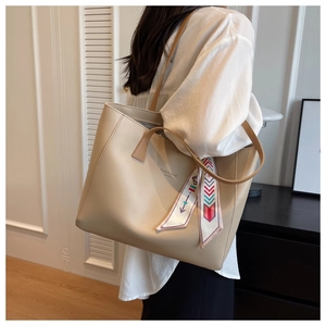 Detailed view of beige tote bag featuring a decorative silk scarf and fashion logo print
