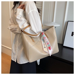 Detail of minimalist tote bag with contrast handles and decorative geometric silk scarf