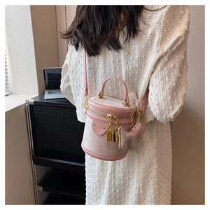 Detail of pink jacquard bucket bag with golden hardware and dog charm on a model